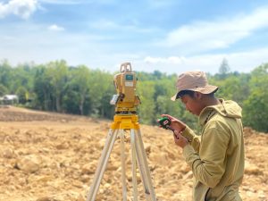 Surveyor melakukan pengukuran topografi menggunakan Total Station di lapangan