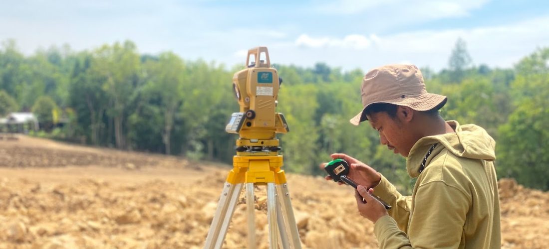 Surveyor melakukan pengukuran topografi menggunakan Total Station di lapangan
