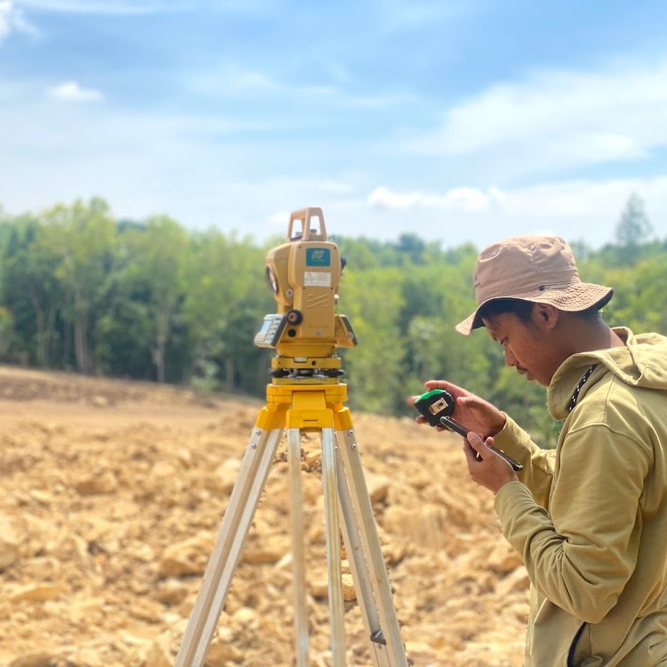Surveyor melakukan pengukuran topografi menggunakan Total Station di lapangan