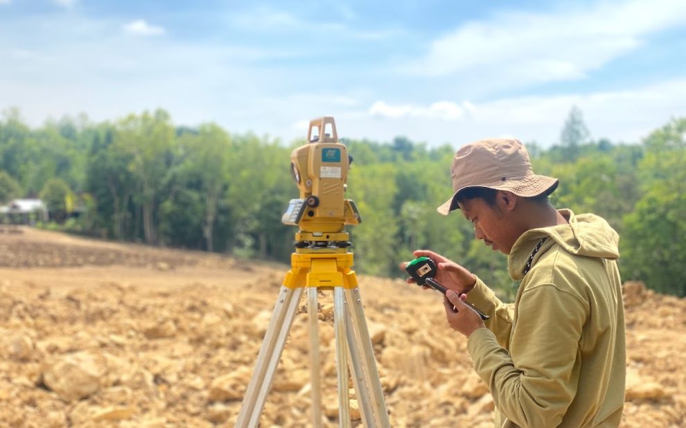 Surveyor melakukan pengukuran topografi menggunakan Total Station di lapangan